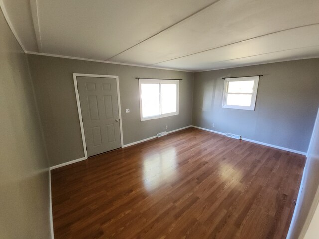 empty room with ornamental molding and wood-type flooring