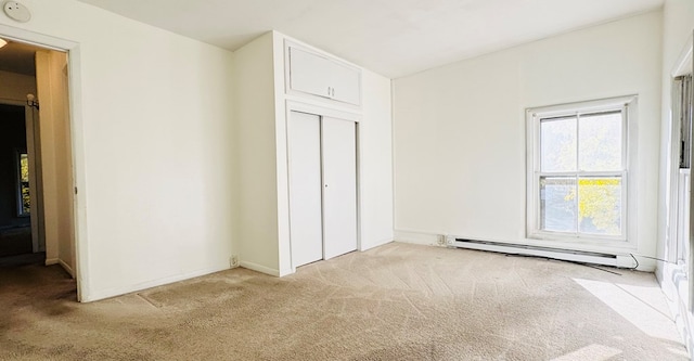 unfurnished bedroom featuring light carpet, a closet, and baseboard heating