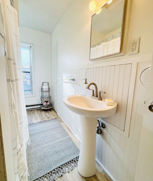 bathroom with wood-type flooring, a baseboard radiator, and wooden walls