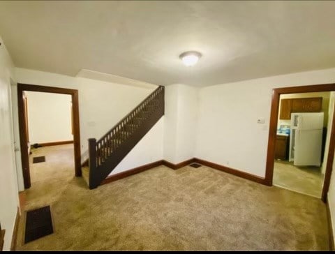 basement featuring white fridge and light colored carpet