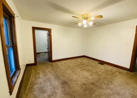 carpeted spare room featuring ceiling fan