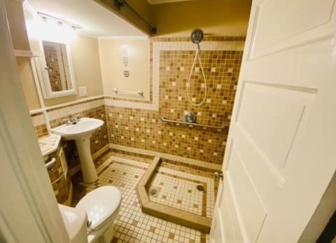 bathroom featuring tile patterned floors, toilet, sink, tile walls, and ornamental molding