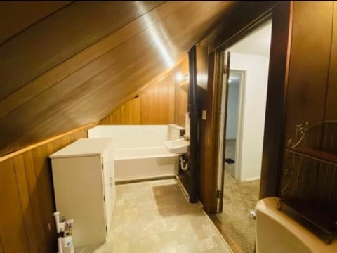 bonus room featuring vaulted ceiling and wood walls