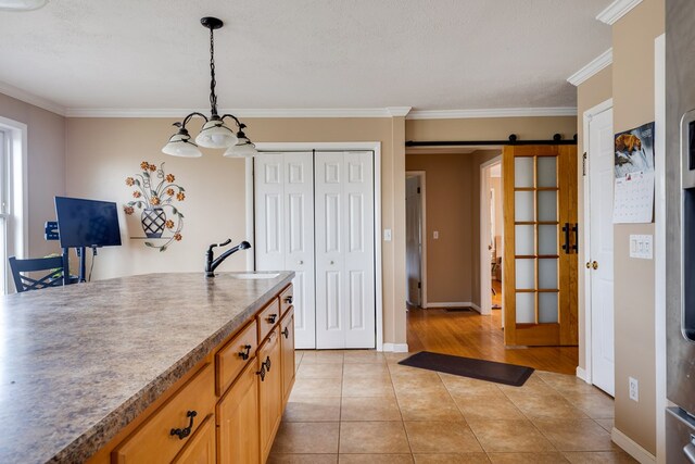 kitchen with a barn door, decorative light fixtures, crown molding, and sink