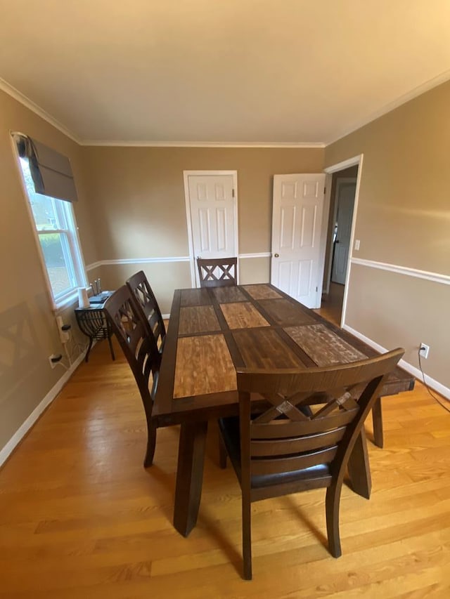 dining room with light wood-type flooring and crown molding