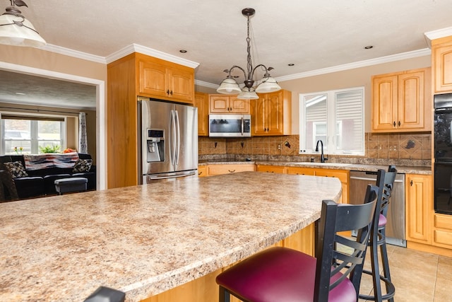 kitchen with pendant lighting, sink, a kitchen bar, stainless steel appliances, and a chandelier