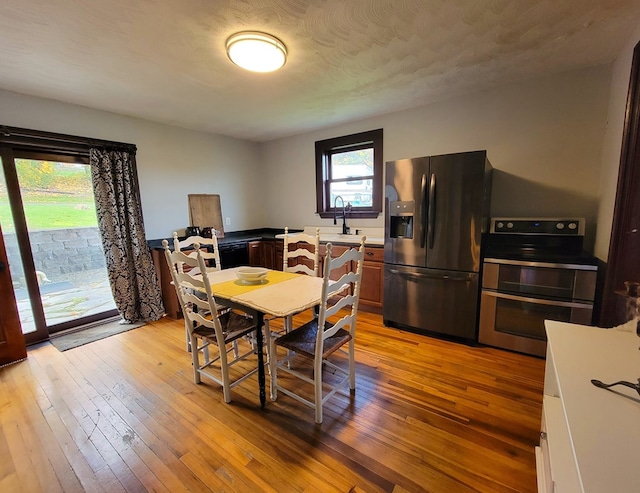 dining space with sink, light wood-type flooring, and a textured ceiling