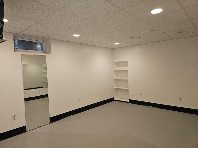 unfurnished room with concrete flooring and a drop ceiling