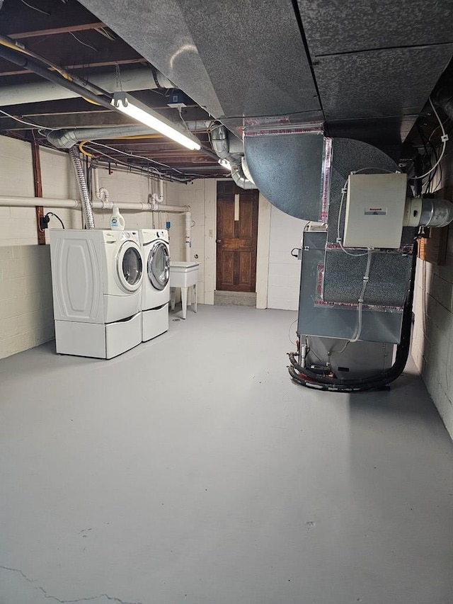 basement with sink, separate washer and dryer, and heating unit