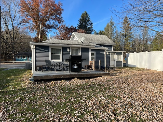 rear view of property with a wooden deck, central AC, and a yard