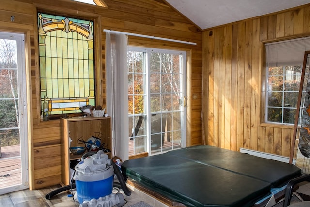 doorway to outside with baseboard heating, wooden walls, and vaulted ceiling