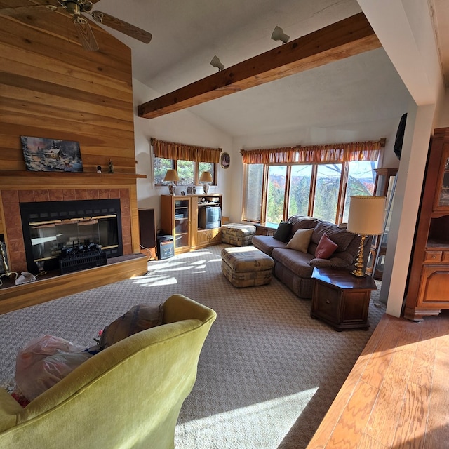 living room featuring a tiled fireplace, lofted ceiling with beams, dark hardwood / wood-style floors, and ceiling fan