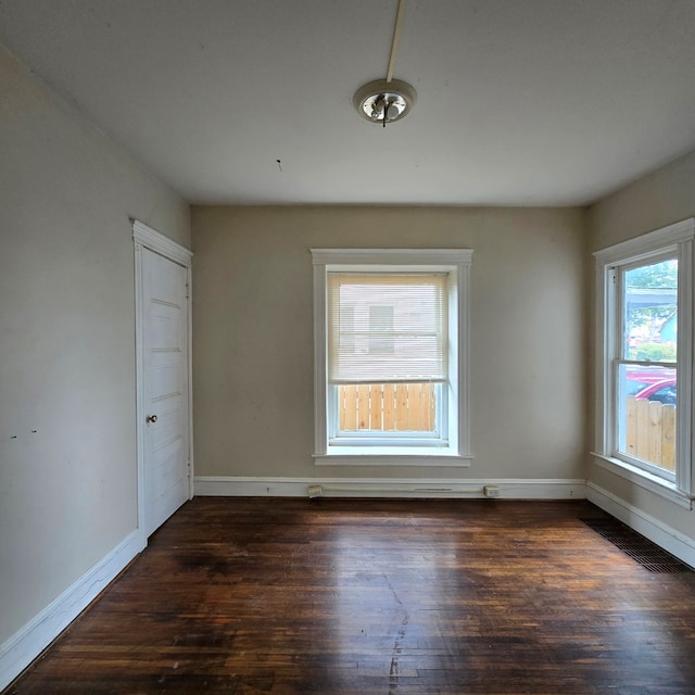 spare room featuring dark hardwood / wood-style flooring and a healthy amount of sunlight