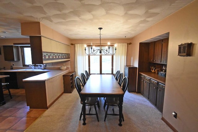 dining space featuring a healthy amount of sunlight, sink, and a notable chandelier