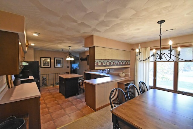 kitchen with a center island, a kitchen breakfast bar, kitchen peninsula, a notable chandelier, and pendant lighting