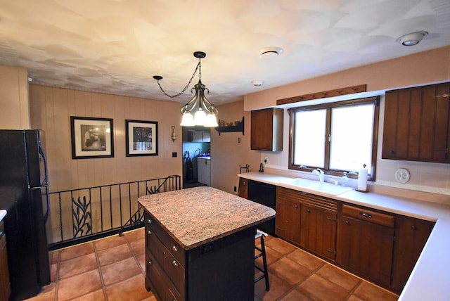 kitchen featuring pendant lighting, sink, a breakfast bar, a center island, and black fridge