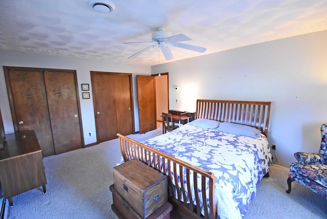 carpeted bedroom with multiple closets and ceiling fan