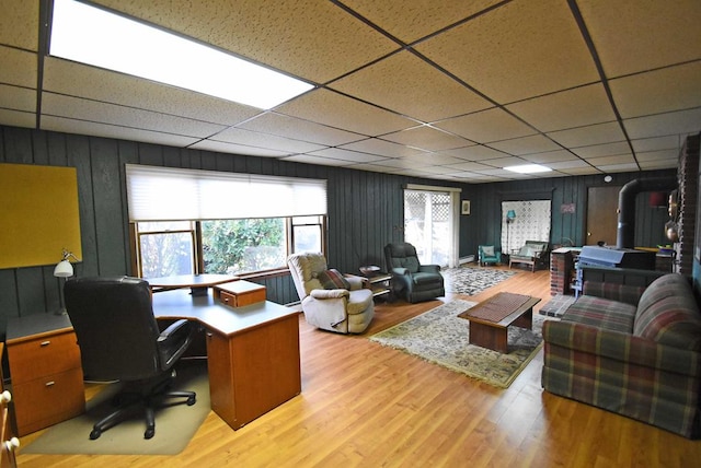 home office with a drop ceiling and light hardwood / wood-style floors