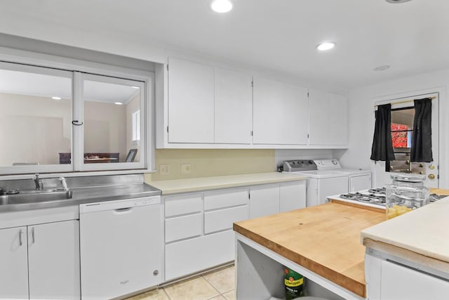 kitchen featuring light tile patterned floors, white dishwasher, washing machine and dryer, white cabinets, and sink