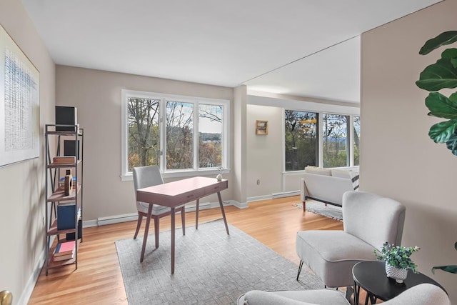 home office featuring a baseboard heating unit and light hardwood / wood-style flooring