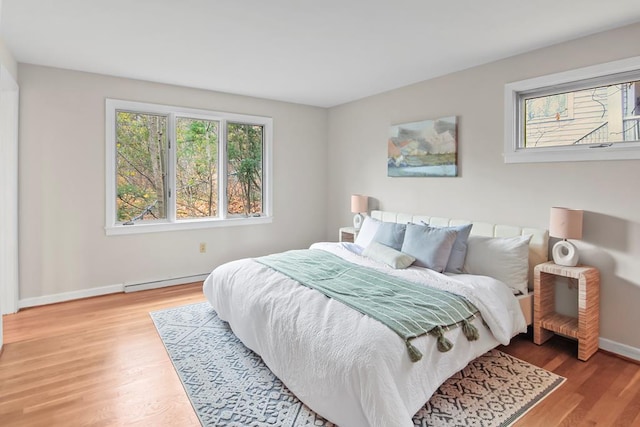 bedroom featuring hardwood / wood-style floors and a baseboard heating unit