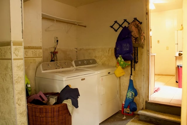 washroom with tile walls and separate washer and dryer