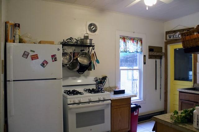 kitchen with light tile patterned floors, white appliances, and ceiling fan