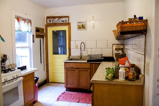 kitchen featuring light tile patterned floors, tasteful backsplash, sink, and white range with gas stovetop