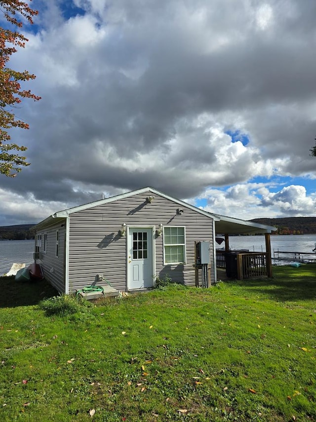 view of outbuilding with a lawn and a water view