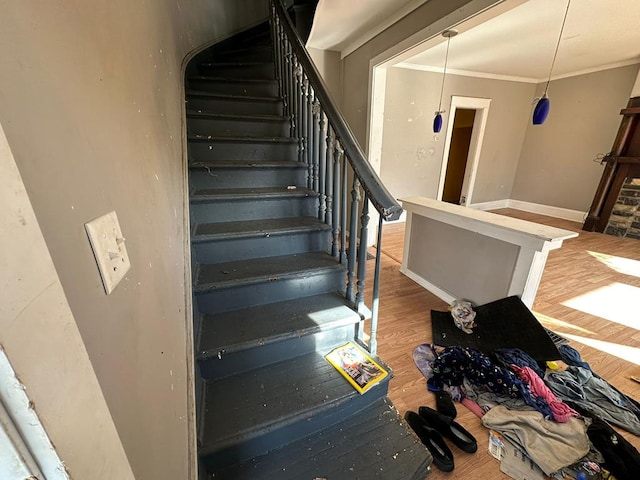 stairway with wood-type flooring and crown molding