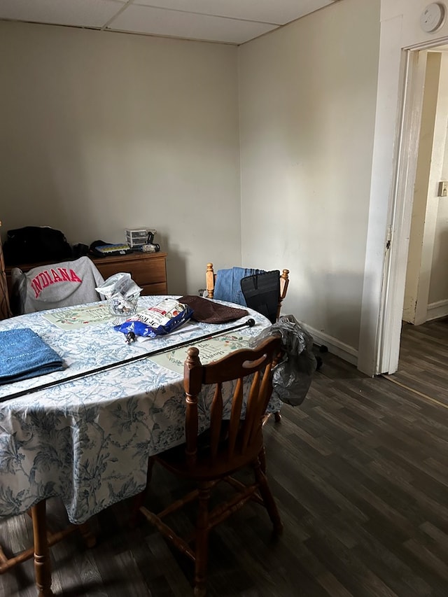 dining area with dark wood-type flooring and a paneled ceiling