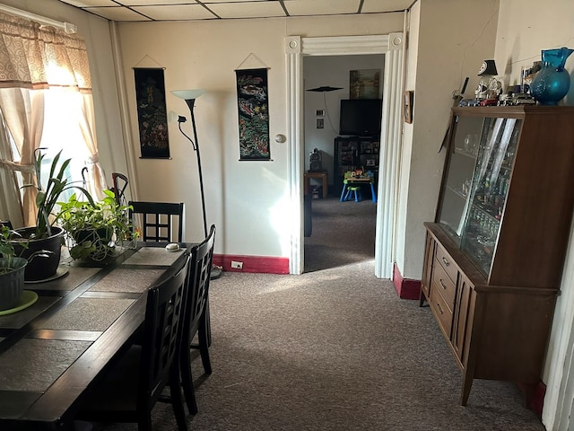 carpeted dining area with a paneled ceiling