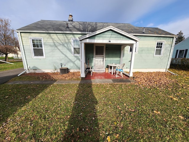 back of property with a lawn, covered porch, and central AC unit