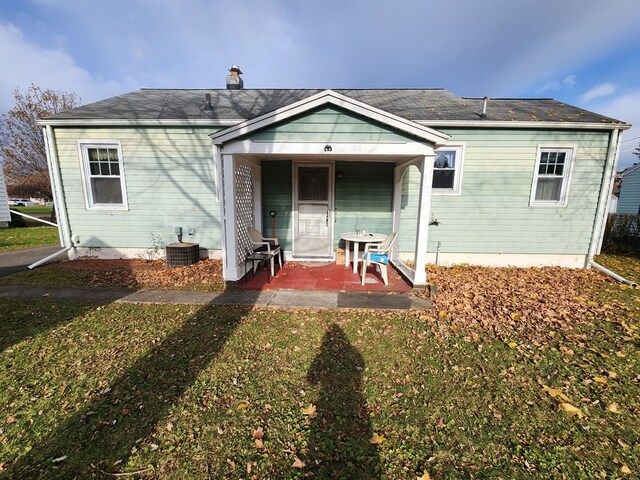 rear view of house with a lawn, central air condition unit, and a porch