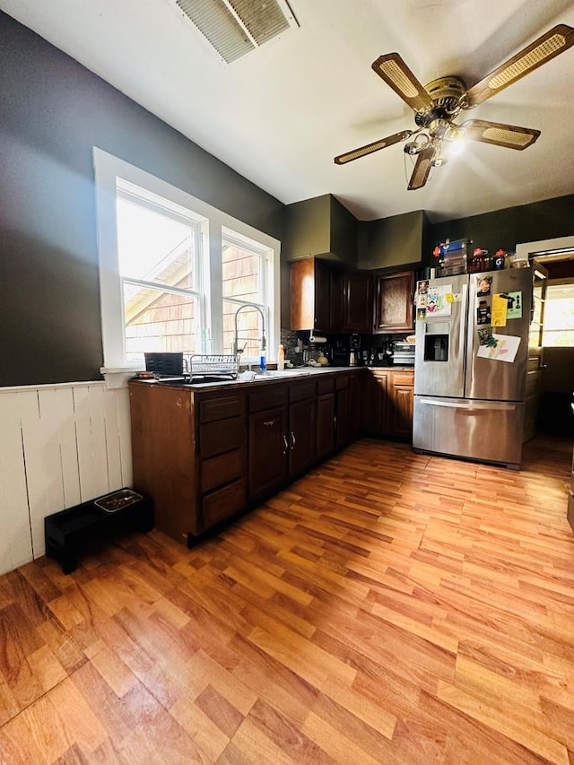 kitchen with dark brown cabinetry, stainless steel fridge with ice dispenser, sink, and light wood-type flooring