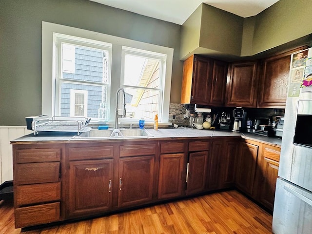 kitchen with backsplash, stainless steel fridge, light hardwood / wood-style flooring, and sink