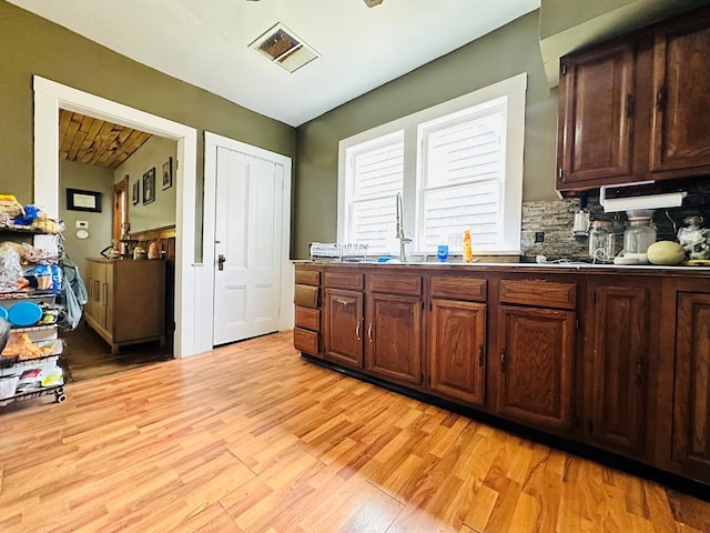 kitchen featuring tasteful backsplash, dark brown cabinetry, sink, and light hardwood / wood-style flooring