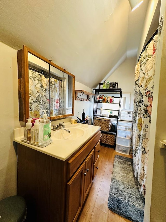 kitchen with light wood-type flooring, vaulted ceiling, and sink