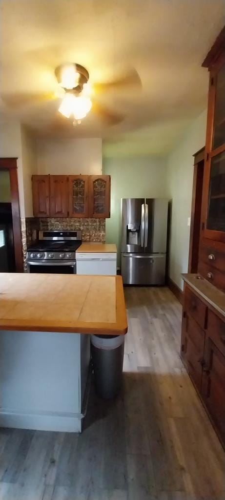 kitchen with a kitchen breakfast bar, stainless steel appliances, wood-type flooring, and tasteful backsplash