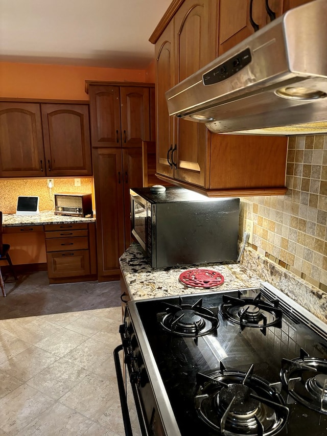 kitchen with stainless steel range, tasteful backsplash, and light stone counters