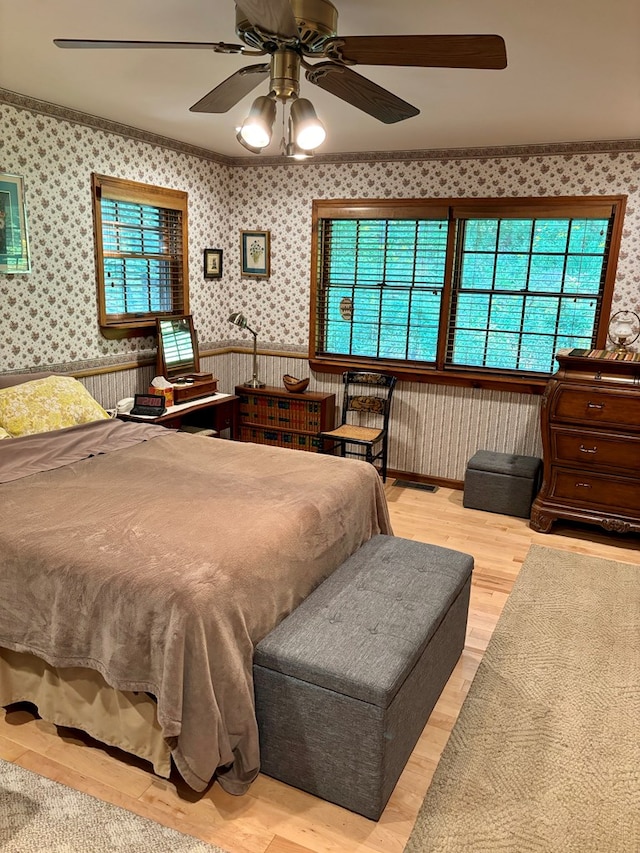 bedroom featuring multiple windows, ceiling fan, ornamental molding, and light hardwood / wood-style flooring