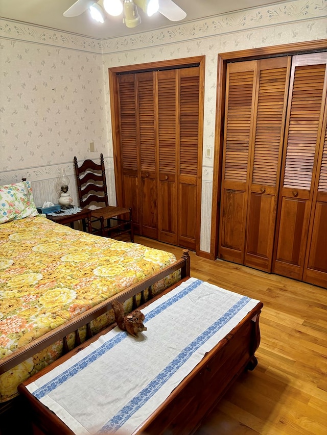 bedroom with two closets, ceiling fan, and light hardwood / wood-style floors