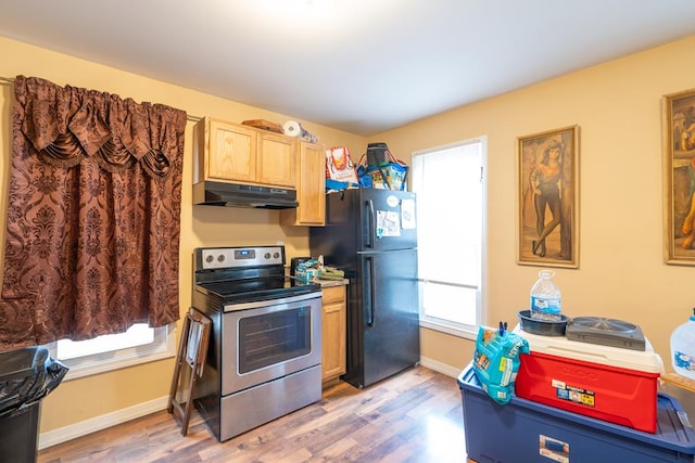 kitchen featuring black refrigerator, plenty of natural light, stainless steel range with electric cooktop, and light hardwood / wood-style flooring