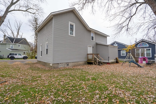 rear view of house featuring a playground and a yard