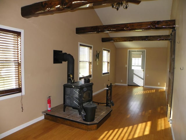 living room with hardwood / wood-style flooring, a wood stove, and vaulted ceiling with beams