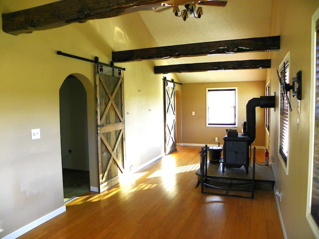 workout room featuring hardwood / wood-style flooring, vaulted ceiling, and a barn door