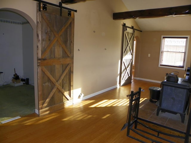 living room with lofted ceiling with beams, wood-type flooring, and a barn door