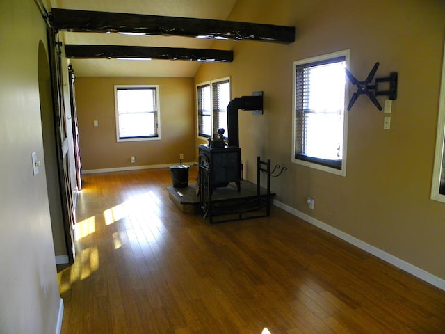 workout room with hardwood / wood-style flooring, vaulted ceiling, and a wood stove