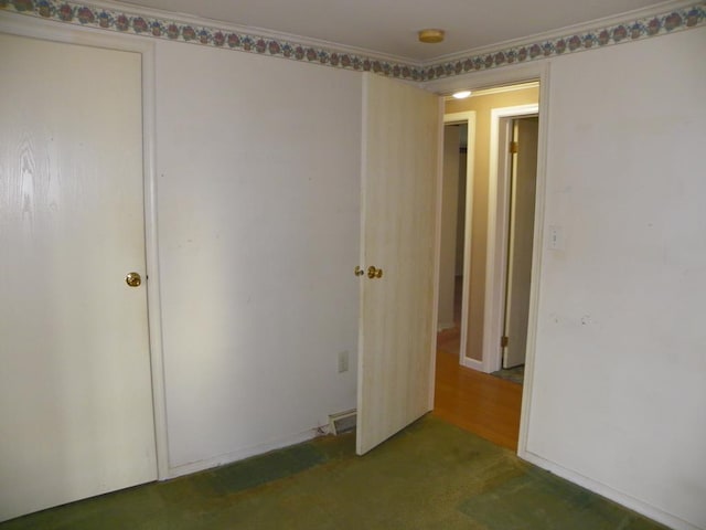 unfurnished bedroom featuring crown molding and dark colored carpet