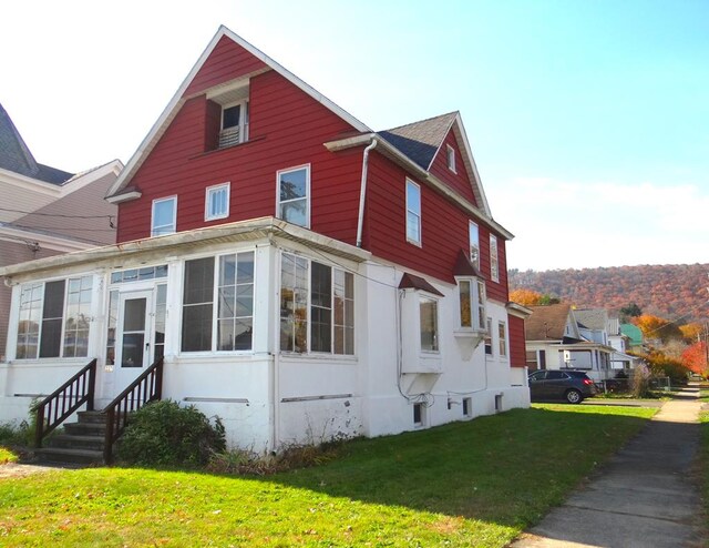 view of side of property with a sunroom and a yard